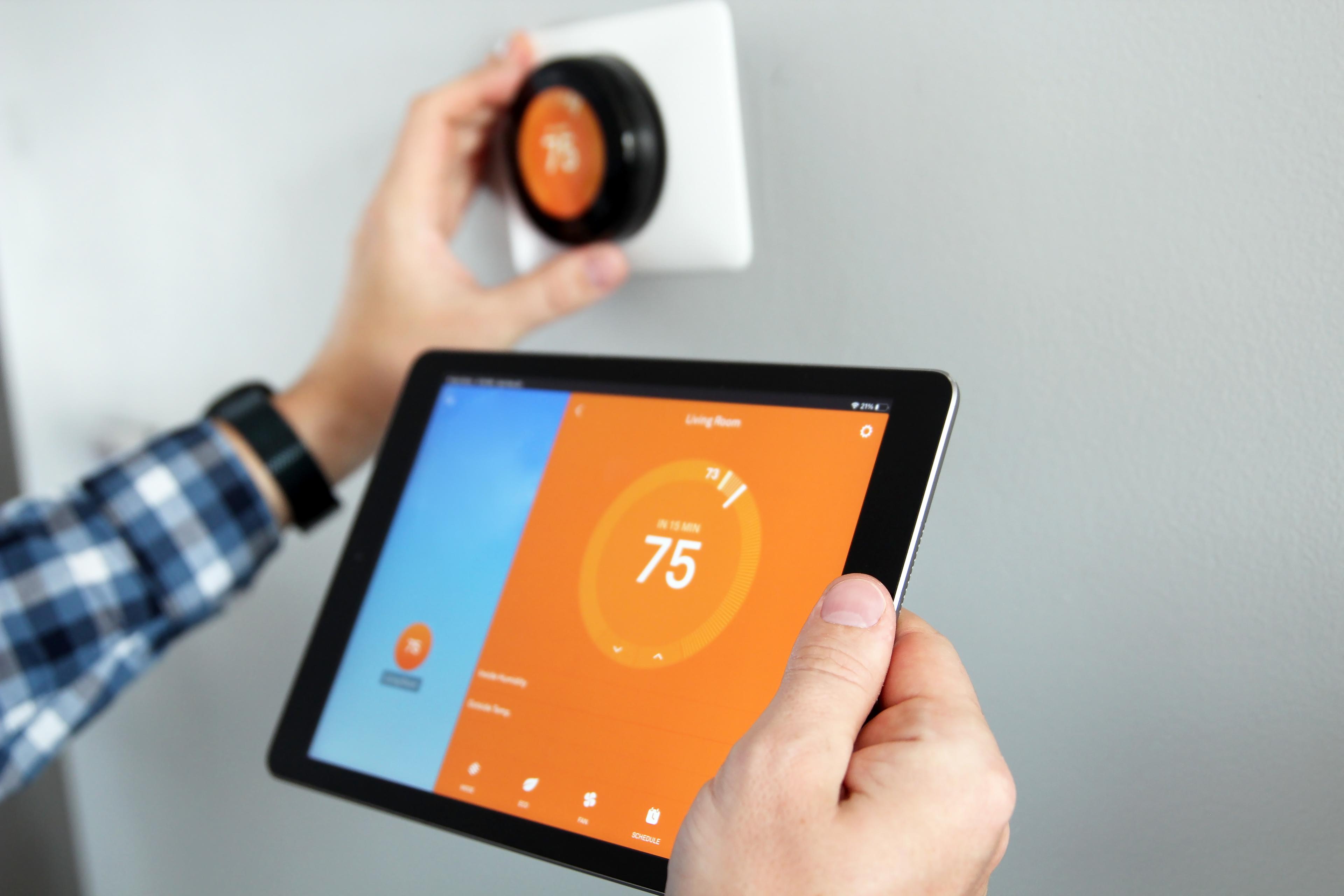 A person increasing the heat in their home using a smart thermostat
